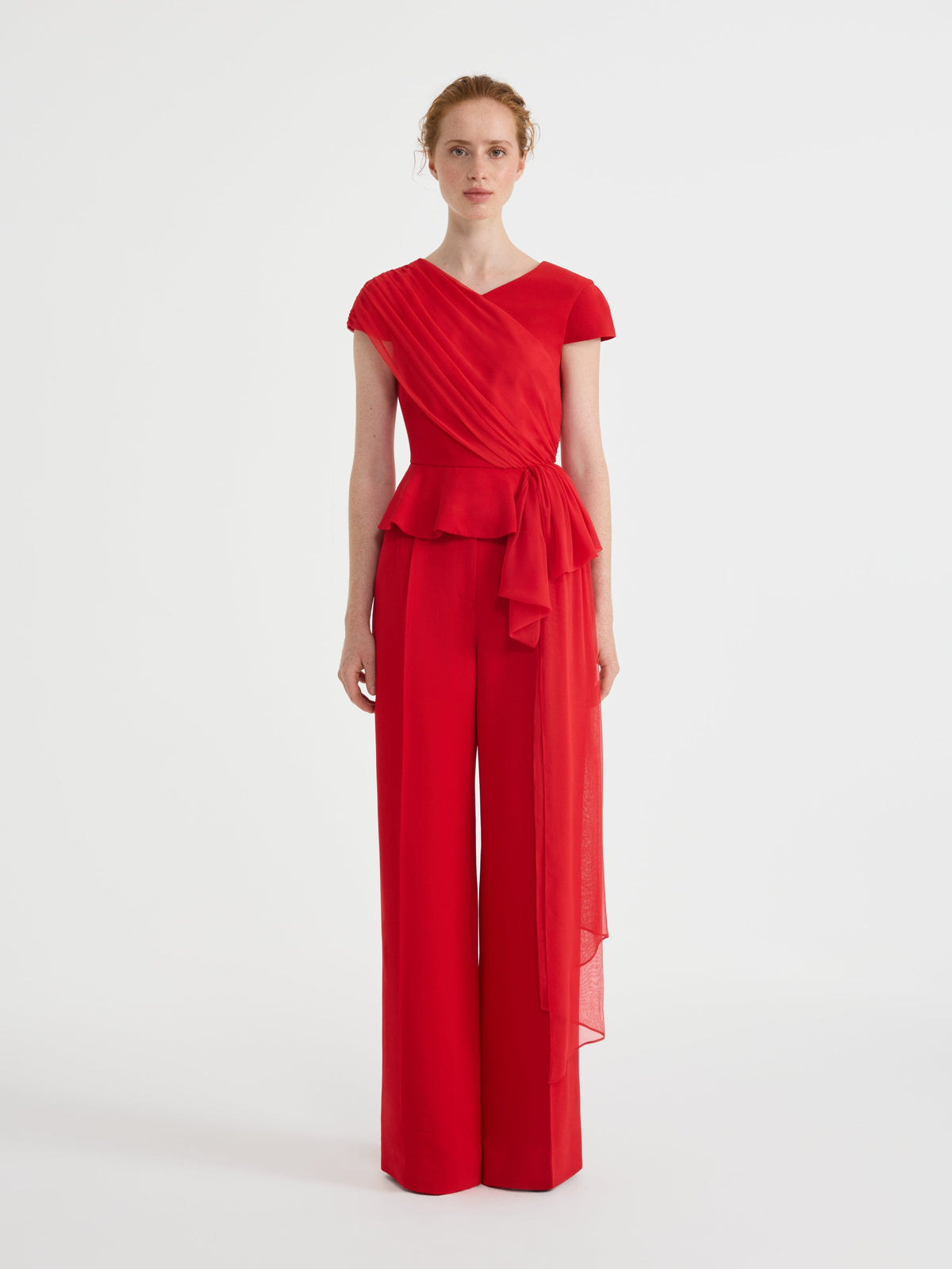 Red V-neck peplum top with draped sash and bow and wide tailored trousers, on model front view