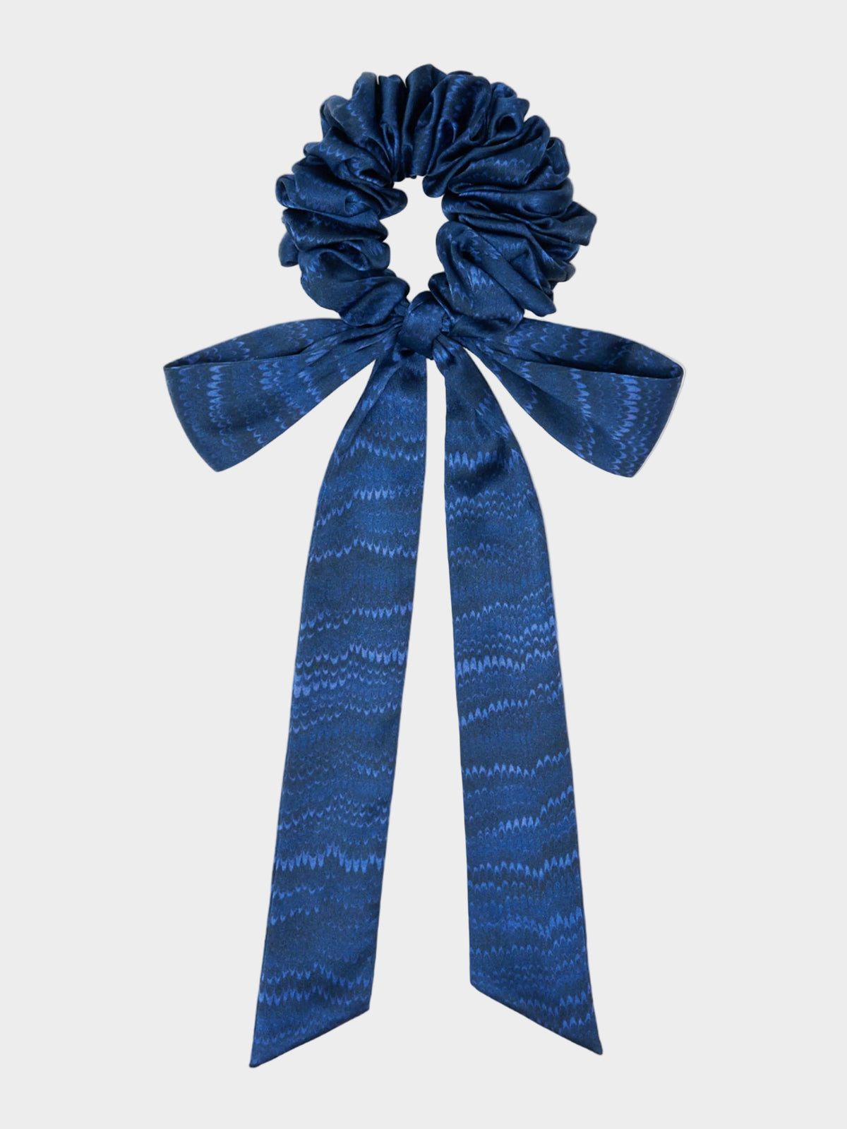 A navy scrunchie with a marbled pattern and a bow on top.
